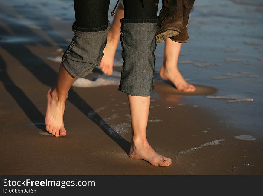 Two pairs female legs on wet sand. Two pairs female legs on wet sand