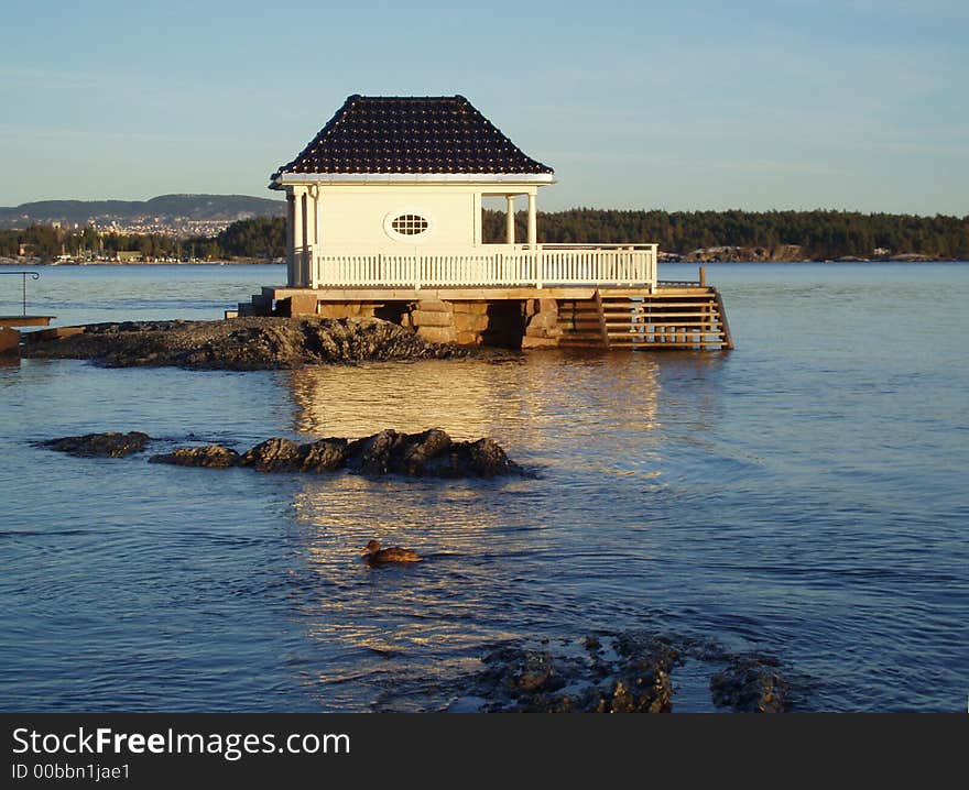 A bathhouse with terasses and stairs to the sea. A duck i swimming in the sea. Oslofjorden, Norway.