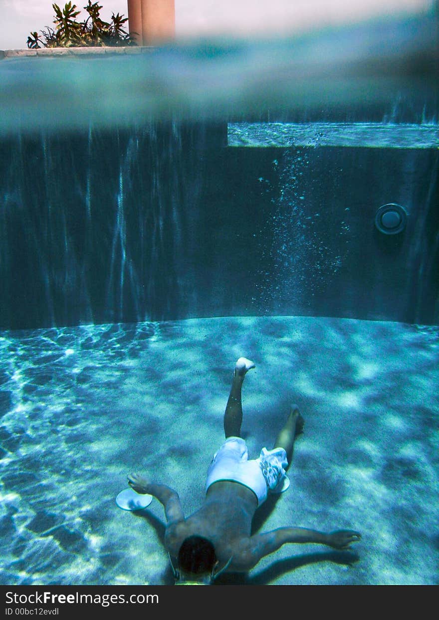 Young man laying on the bottom of a pool in Anguilla. Young man laying on the bottom of a pool in Anguilla