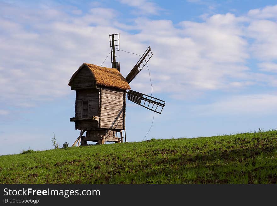 Windmill with a straw roof on a green meadow