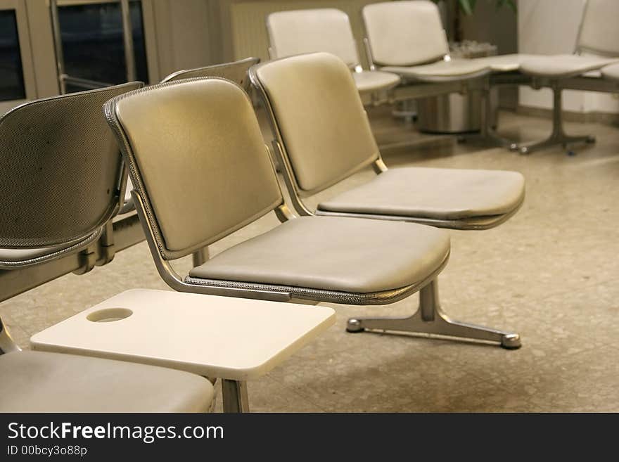 A couple of chairs in the waiting room of an airport departure gate. A couple of chairs in the waiting room of an airport departure gate