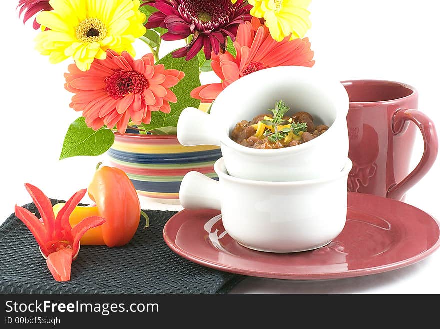 Chili beans served on a table set with a bright bowl of festive spring flowers, with plate,bowls ,cup,colorful peppers and a chili pepper flower. Chili beans served on a table set with a bright bowl of festive spring flowers, with plate,bowls ,cup,colorful peppers and a chili pepper flower.