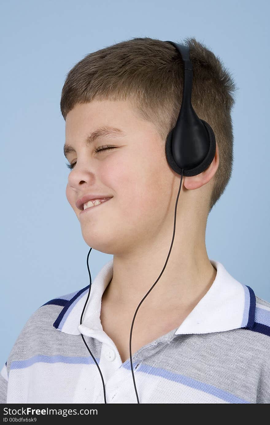 Head shot of a young boy enjoying music on headphones with a blue background. Head shot of a young boy enjoying music on headphones with a blue background.