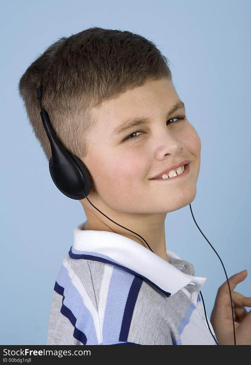 Head shot of a young boy enjoying music on headphones with a blue background. Head shot of a young boy enjoying music on headphones with a blue background.