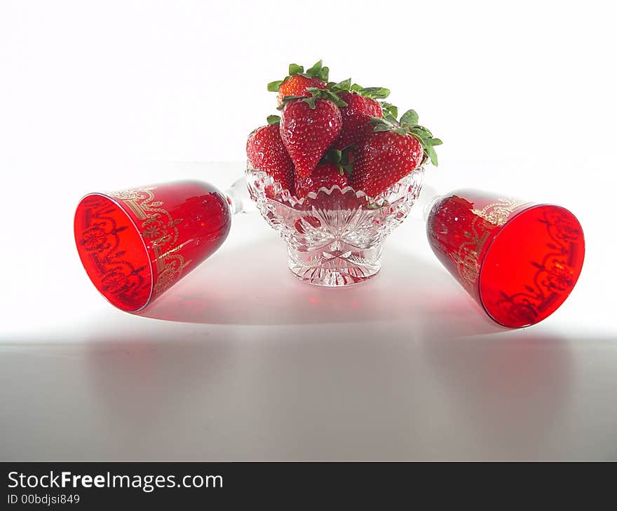 Crystal bowl filled with strawberries including red glasses on a white background. Crystal bowl filled with strawberries including red glasses on a white background.