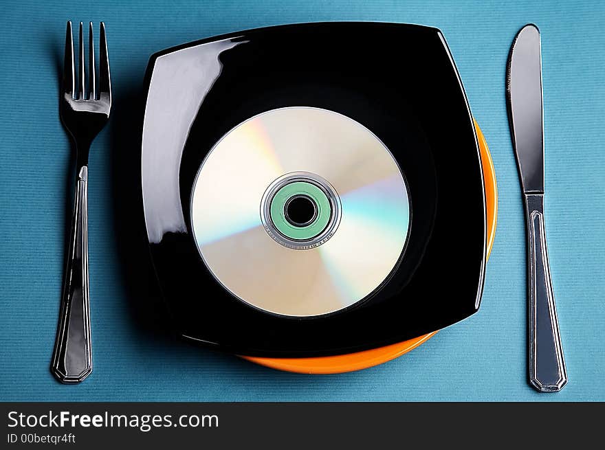 Still-life with disk, knife, fork and plate on blue background. Still-life with disk, knife, fork and plate on blue background