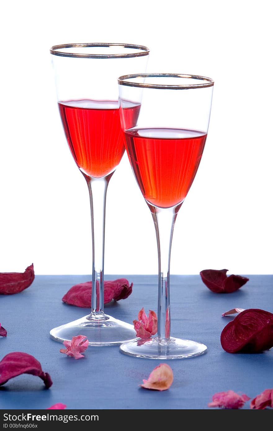 Two glasses of wine on table with rose petals on white background. Two glasses of wine on table with rose petals on white background