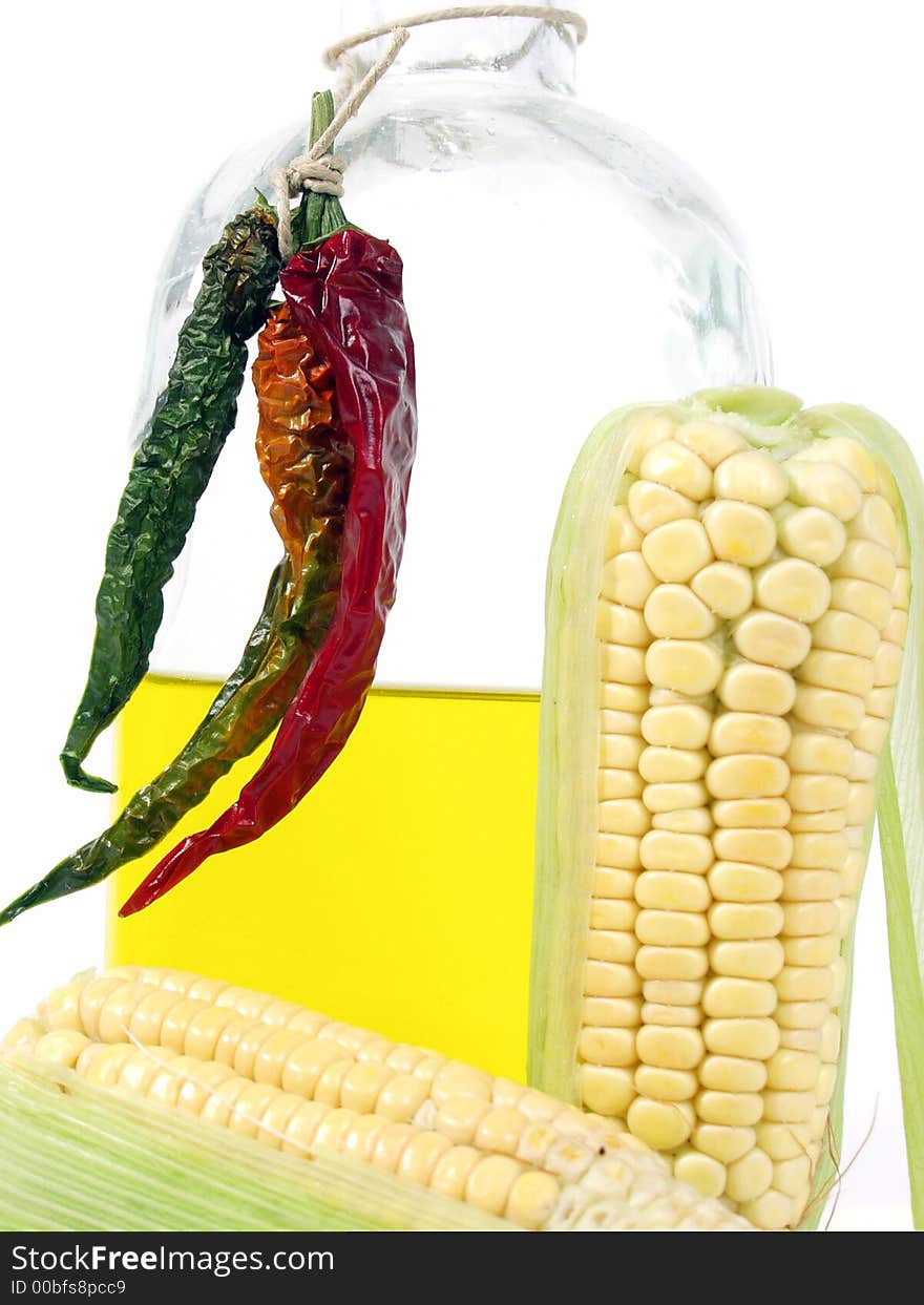 Bottle of yellow oil and fresh corn on the cob with pepper