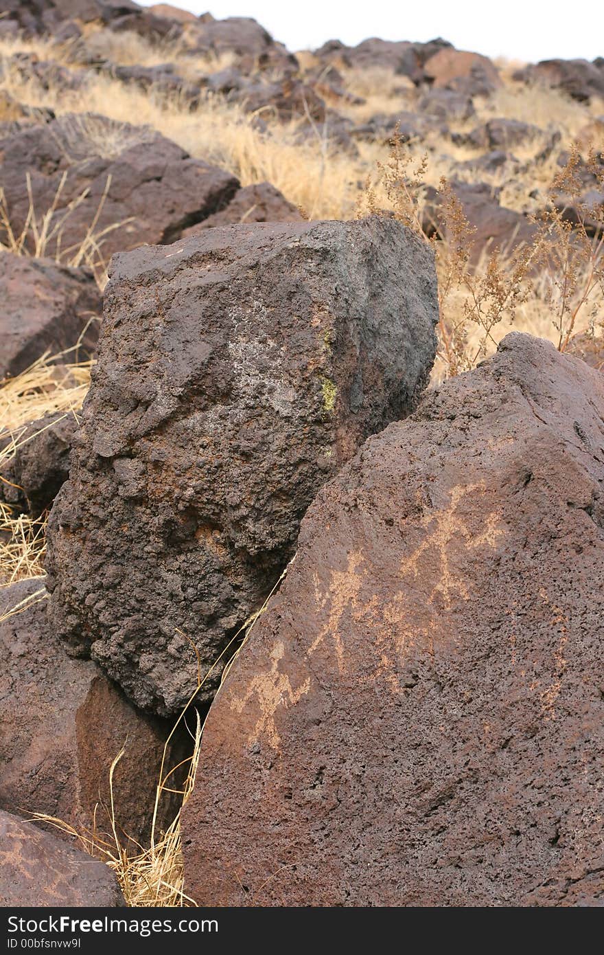 Petroglyph of three figures on volcanic rock