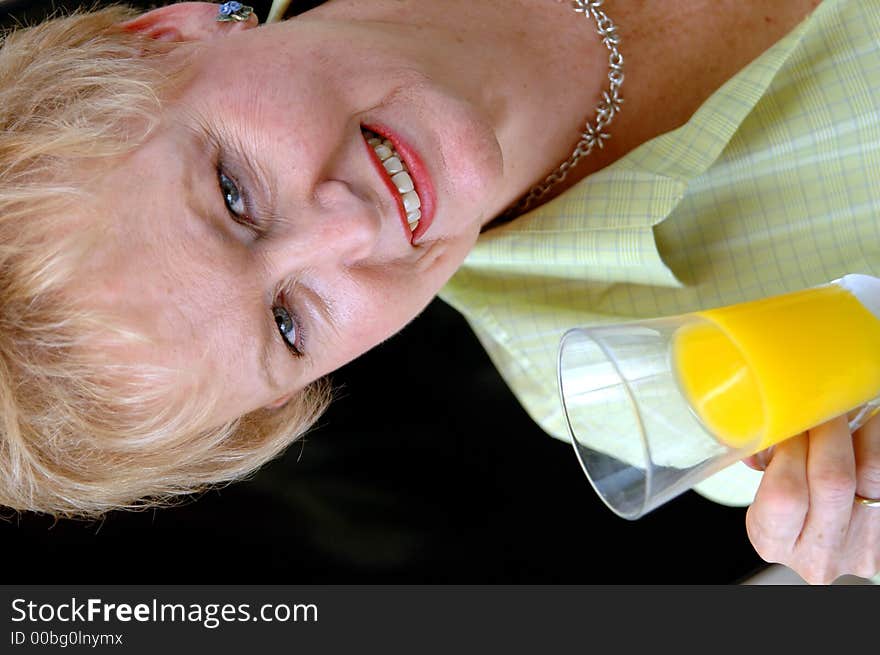 A senior woman holding a glass of orange juice. A senior woman holding a glass of orange juice