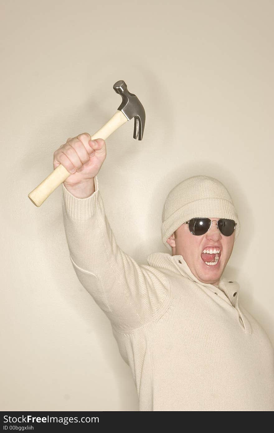 Man with wool sweater and wool hat holds up a hammer in sign of strength. Man with wool sweater and wool hat holds up a hammer in sign of strength