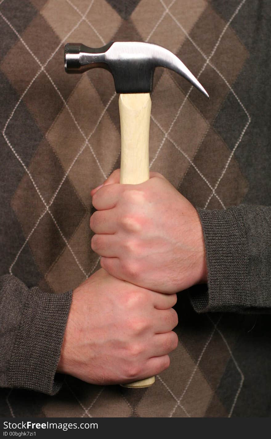 Man holding hammer with both hands in front of him while wearing a sweater in a sign of strength