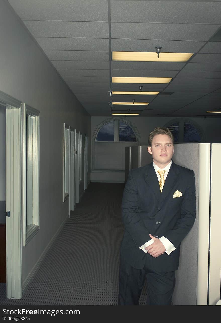 Businessman standing against a wall in the office with his hands folded in front of him