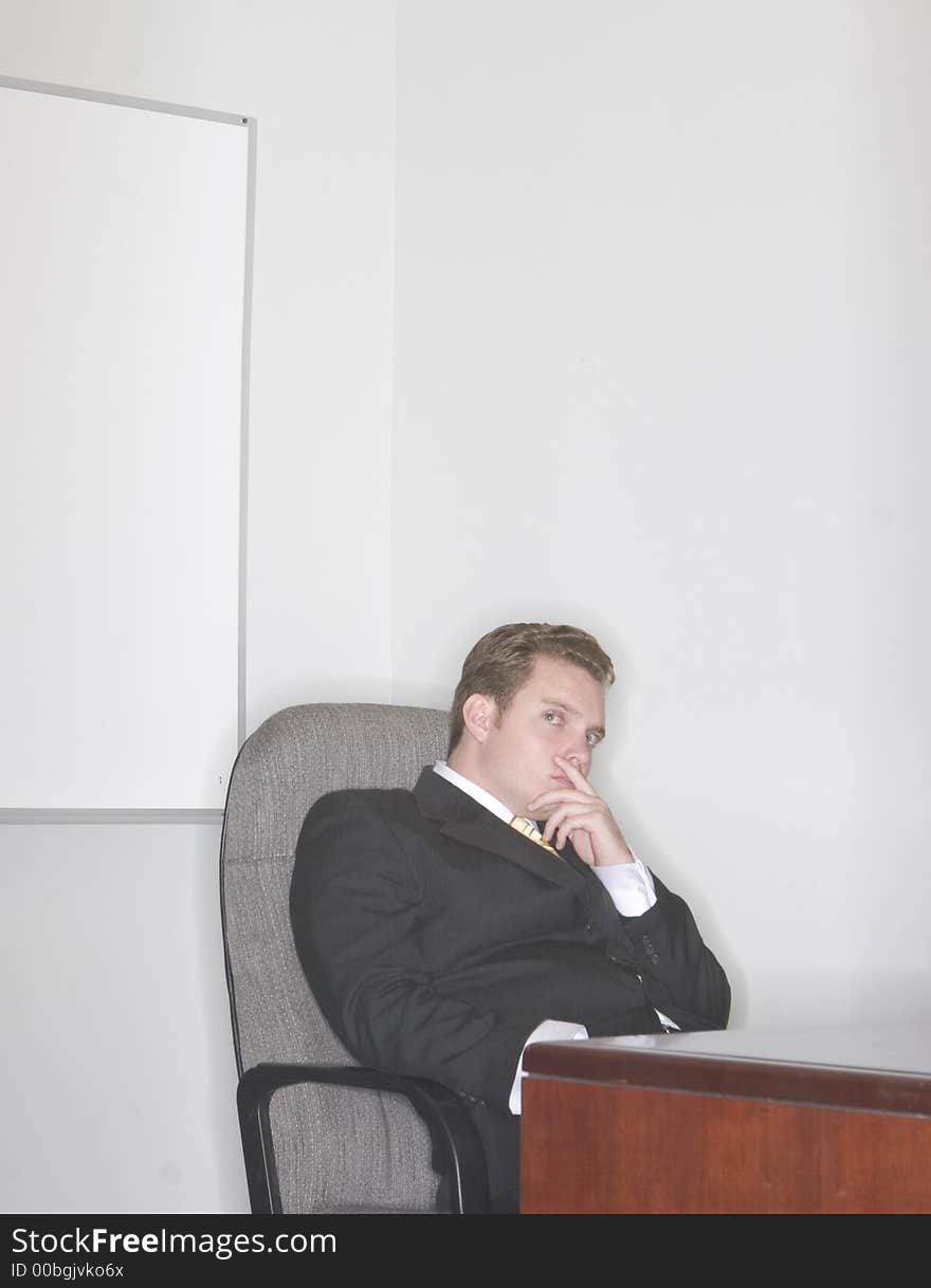 Businessman sitting in his chair with his hand on his chin thinking in his office