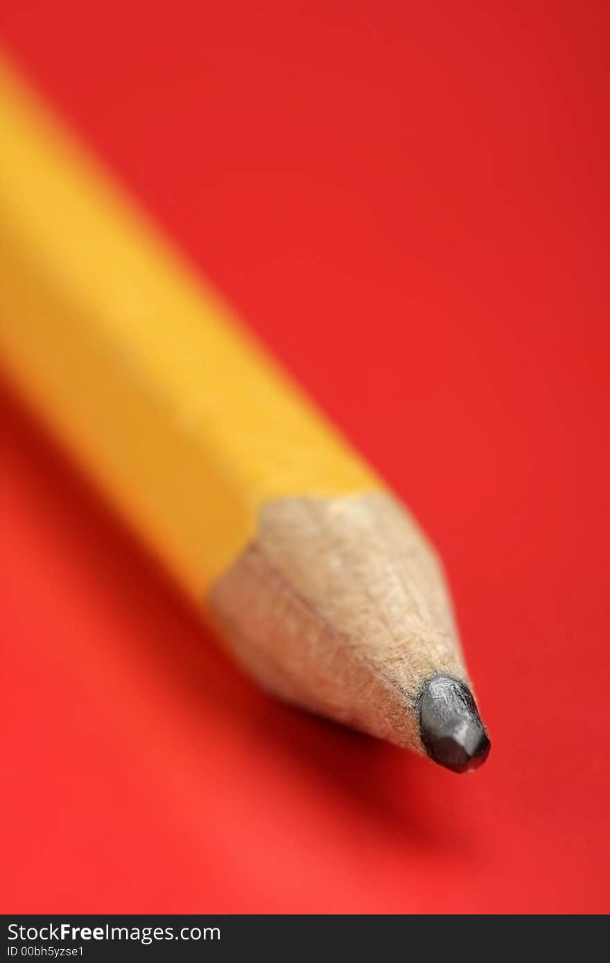 A yellow Pencil in closeup view. Red background. Soft focus.