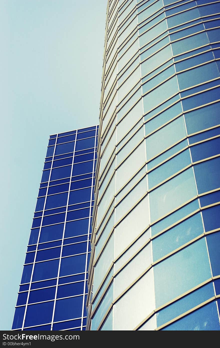 Business building going up towards the sky with blue windows and a glass structure