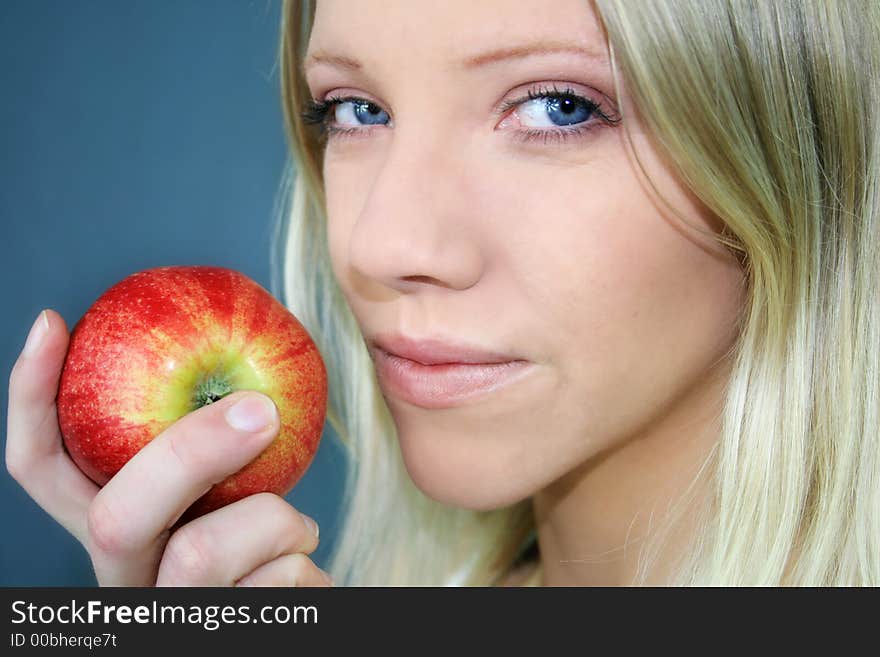 A smiling young blond woman is holding a apple in her hand. A smiling young blond woman is holding a apple in her hand