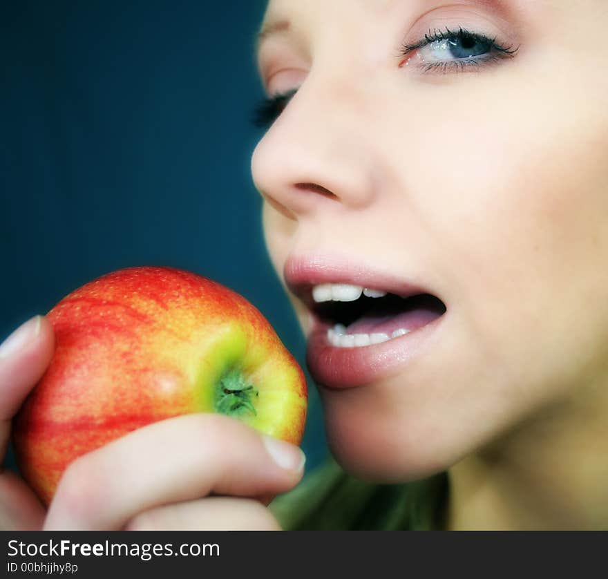 A smiling young blond woman is holding a apple in her hand. A smiling young blond woman is holding a apple in her hand