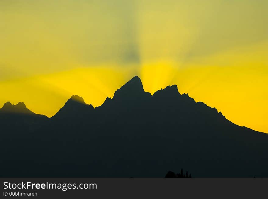 Sunbeams brighten the sky at sunset over the silhouetted mountains in Grand Teton National Park. Sunbeams brighten the sky at sunset over the silhouetted mountains in Grand Teton National Park