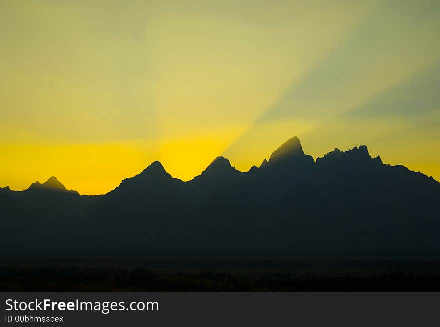 Sunbeams burst over mountains at sunset