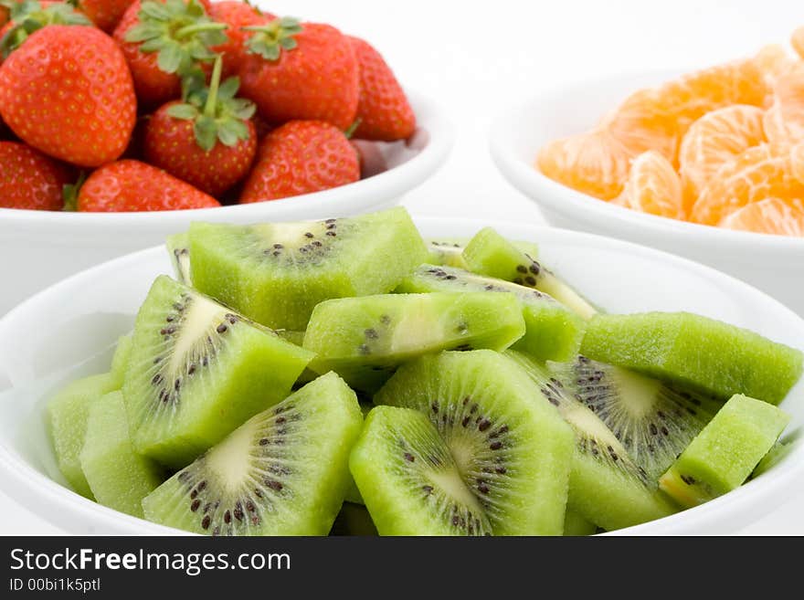 Kiwi, strawberry and mandarine, tangerine in white bowls