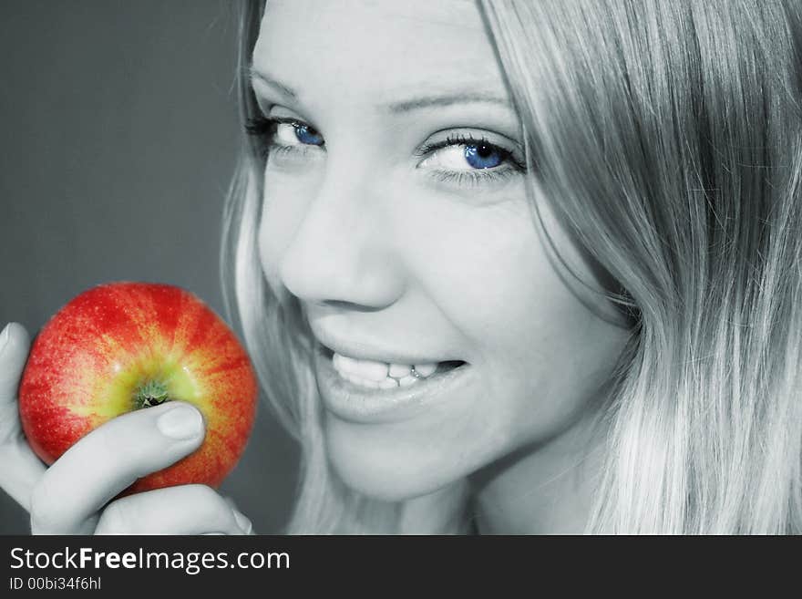 A smiling young blond woman is holding a apple in her hand. A smiling young blond woman is holding a apple in her hand