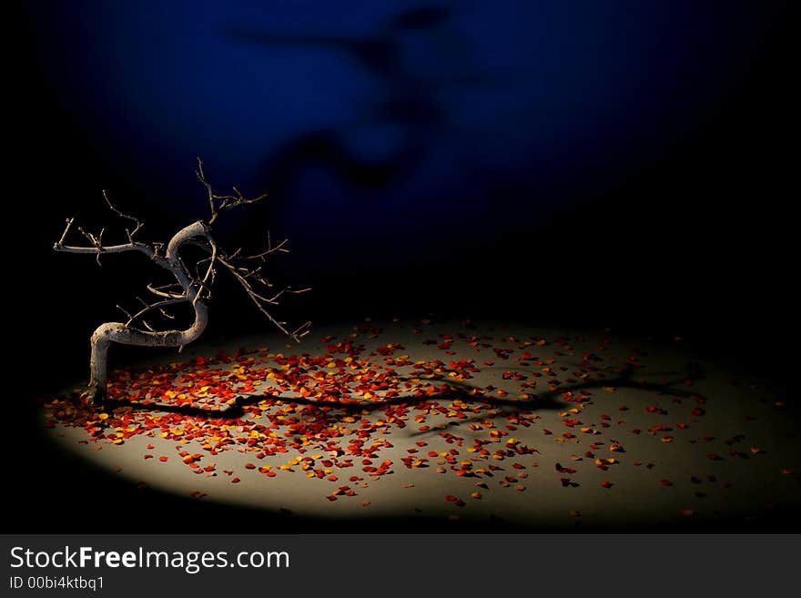 Studio picture. Dramatic artificial autumn. Dead bonsai tree on paperwork lighted by spot lamp and spot-flashed on blue background for thunderfeeling in dramatic mood.