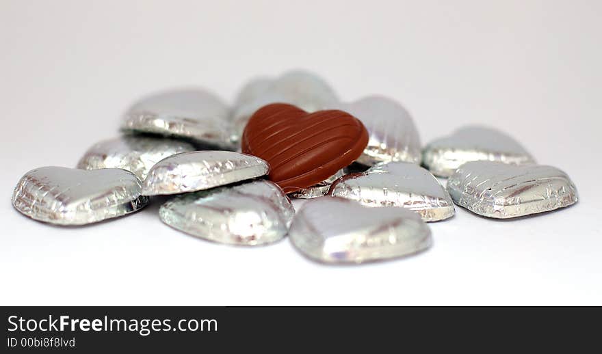 A  chocolate heart is in a sea of silver hearts. A  chocolate heart is in a sea of silver hearts.