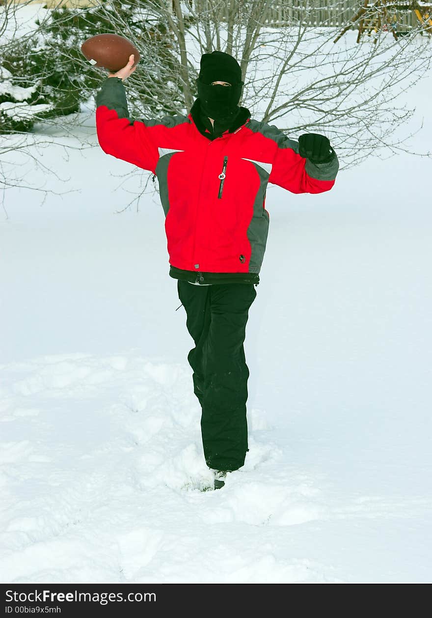 Teen Playing Football in the snow, dressed warmly