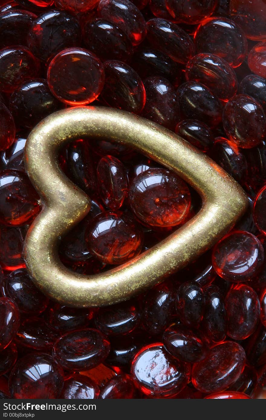 Gold heart lying on red glass beads