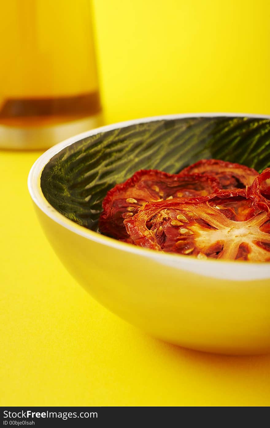 Dried sliced tomatoes in green bowl on the yellow background. Dried sliced tomatoes in green bowl on the yellow background.