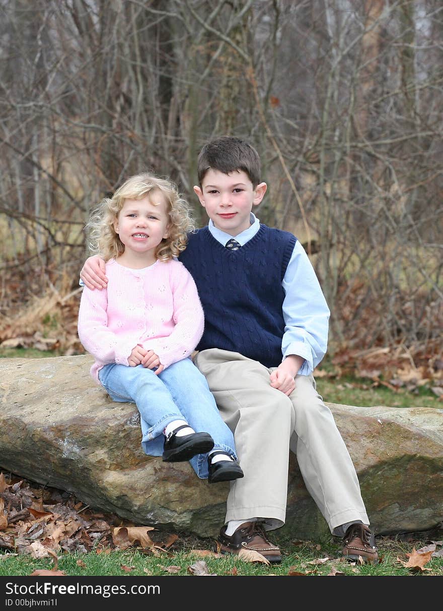 Happy young children siblings in park like setting on rocks. Happy young children siblings in park like setting on rocks.