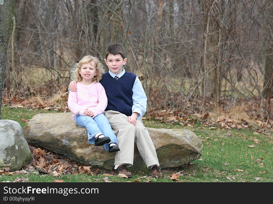 Happy young children siblings in park like setting on rocks. Happy young children siblings in park like setting on rocks.