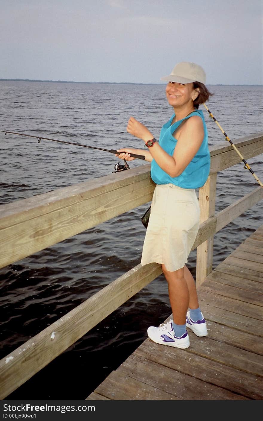 Photo of hispanic woman trying her luck on a Sanibel Island Florida fishing pier. Though no fish were caught that day, being in the outdoors was enjoyable.