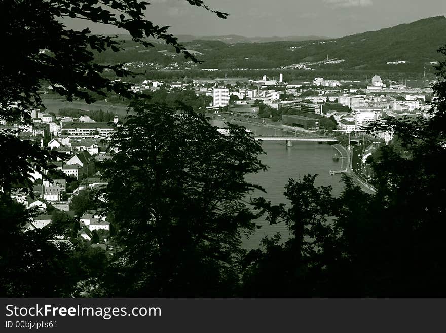 View from a hill (Freinberg) through trees on Linz coloured black and white. On the left side Urfahr (district of Linz) on the right Center of Linz. In the middle the river Danube and the Nibelungen-bridge connecting Urfahr with center-Linz. View from a hill (Freinberg) through trees on Linz coloured black and white. On the left side Urfahr (district of Linz) on the right Center of Linz. In the middle the river Danube and the Nibelungen-bridge connecting Urfahr with center-Linz.