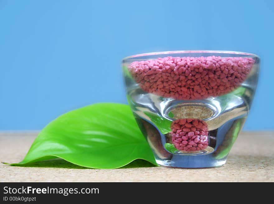 A green leaf with pink stones in a glass - wellness - spa. A green leaf with pink stones in a glass - wellness - spa