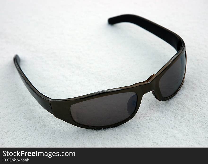 Sunglasses on to snow on a white background