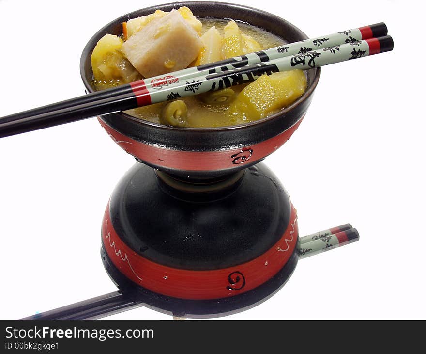 A bowl of chinesse food with reflection on a mirror and chopsticks