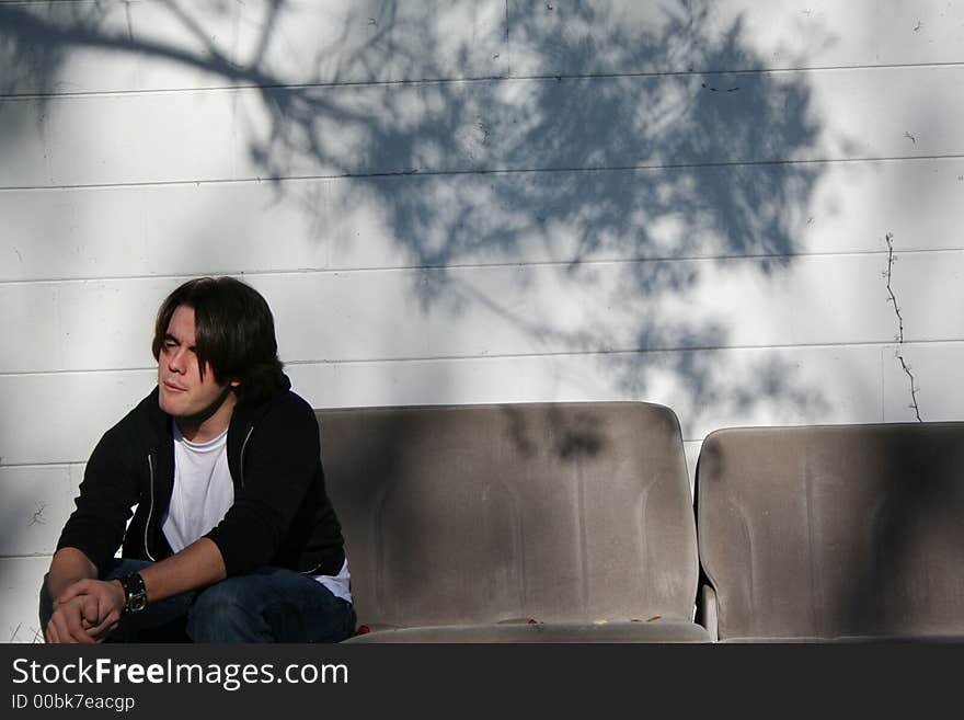 Photo of a young man sitting on car seats outside the building. Photo of a young man sitting on car seats outside the building