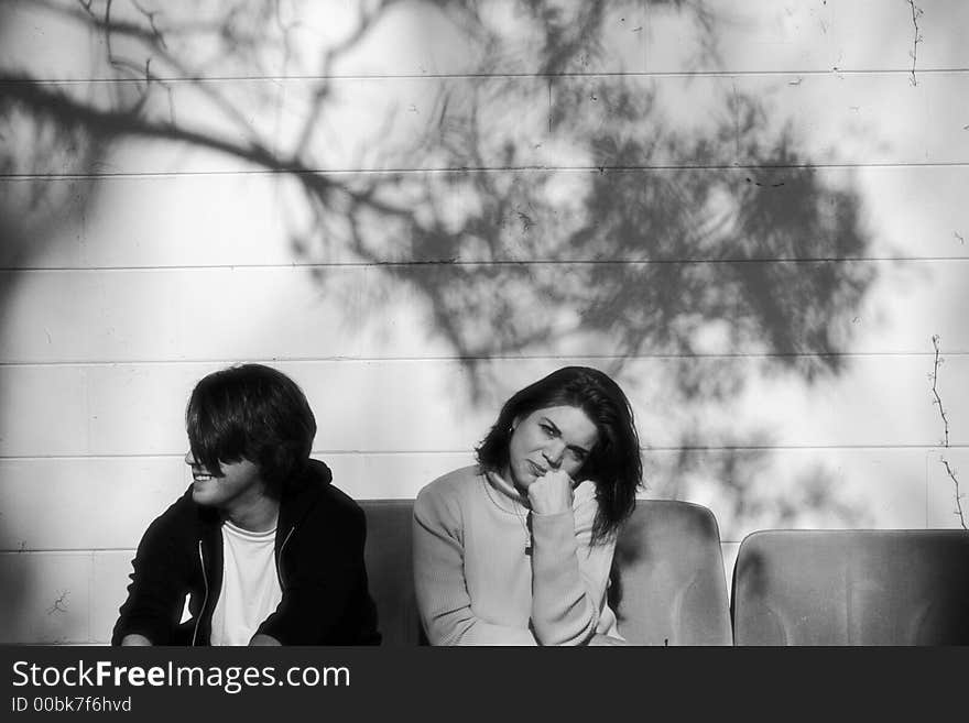 Photo of a young man sitting on car seats outside the building with woman. Photo of a young man sitting on car seats outside the building with woman