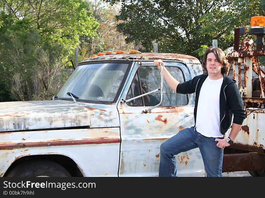 Photo of a young man standing outside by an old abandon truck. Photo of a young man standing outside by an old abandon truck