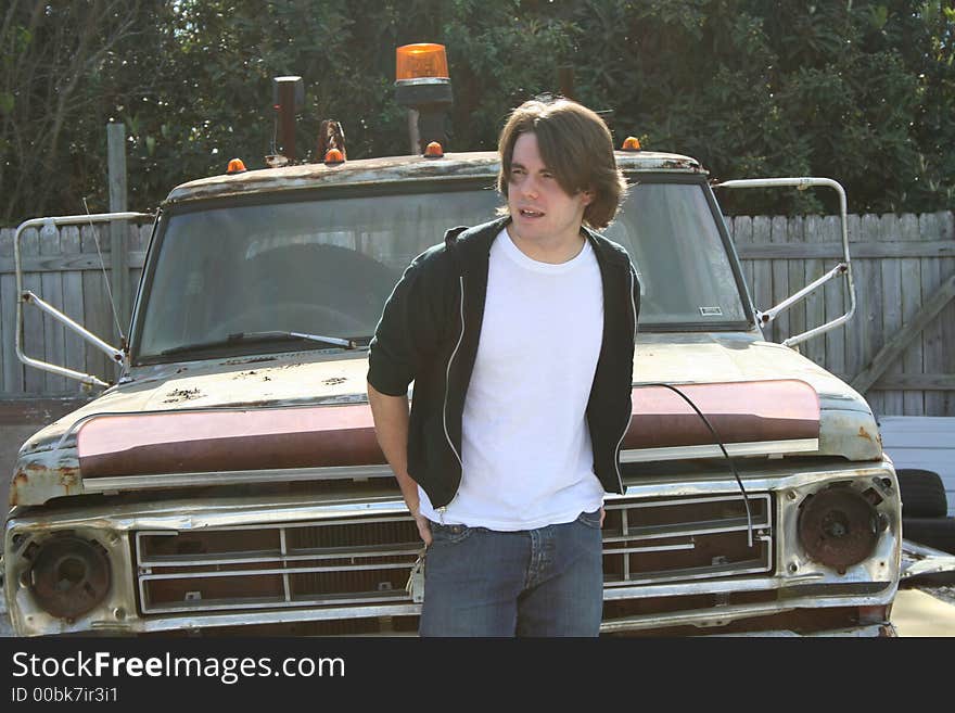 Photo of a young man standing outside by an old abandon truck. Photo of a young man standing outside by an old abandon truck