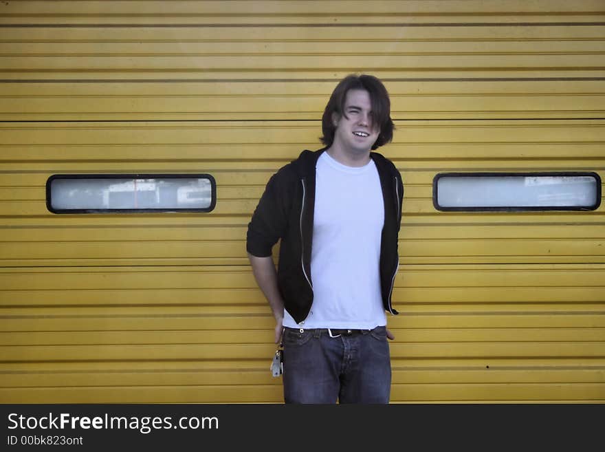 Photo of a young man standing against the overhead doors of an building. Photo of a young man standing against the overhead doors of an building