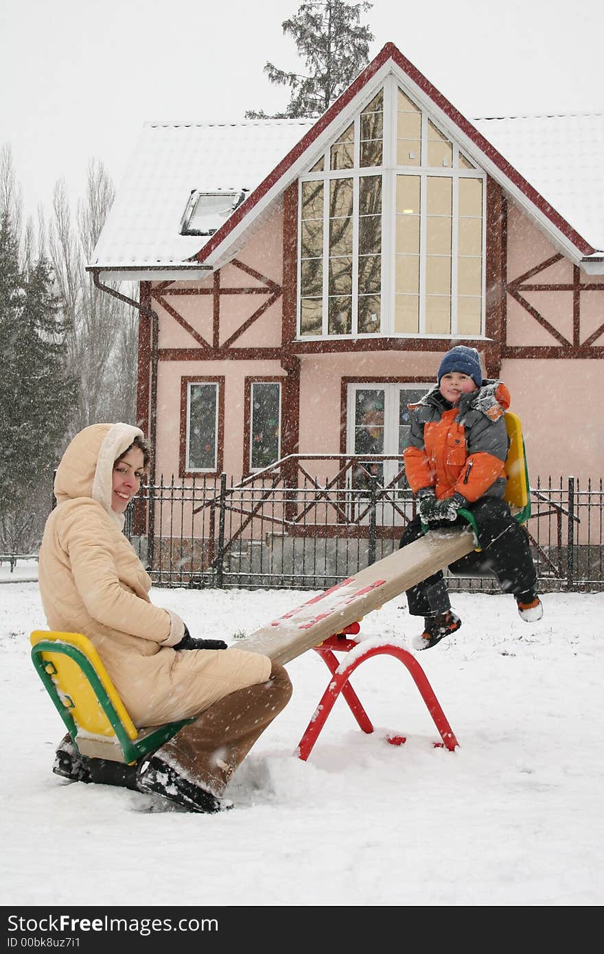 Mother with son on winter seesaw