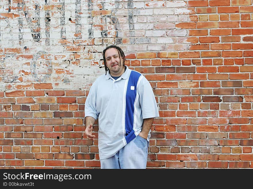 Photo of a young man leaning against a brickwall outside in an downtown area. Photo of a young man leaning against a brickwall outside in an downtown area.