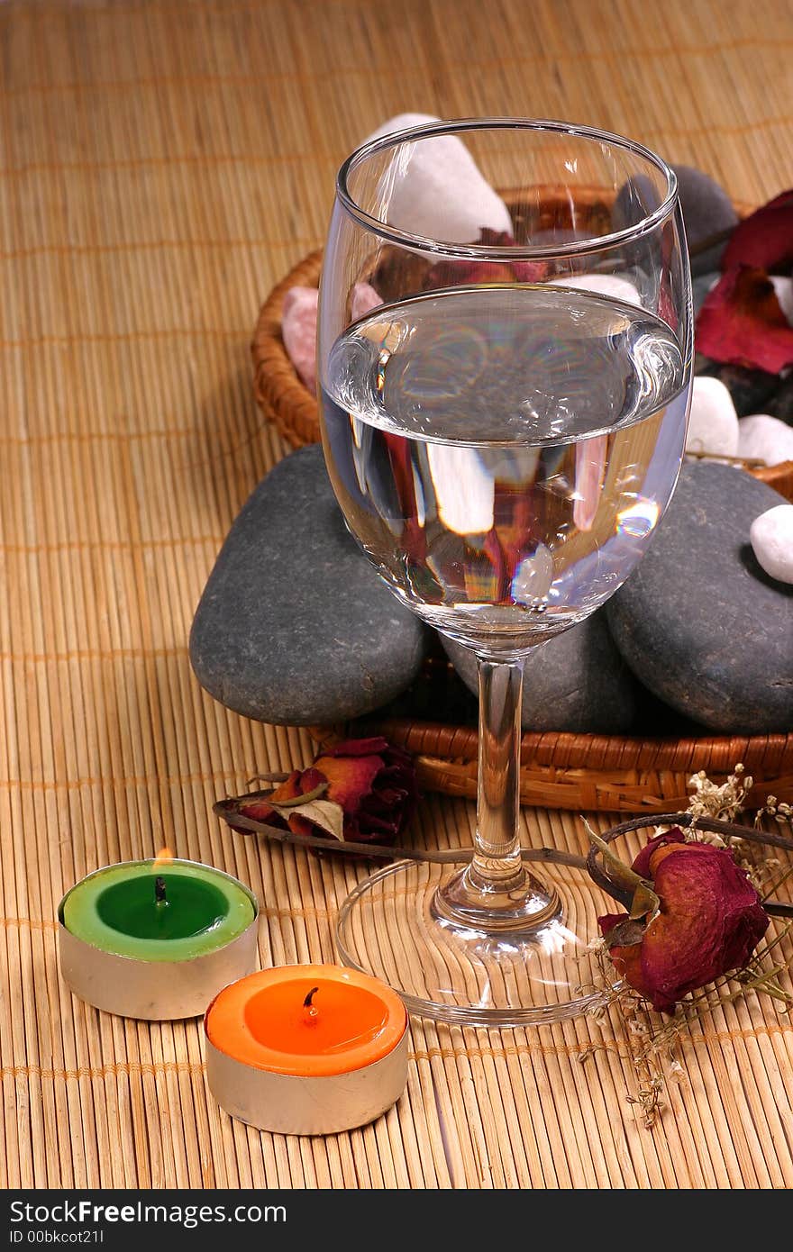 A romance view of a glass, natural pebbles and dried rose petals on the rattan background. Suitable for spa, relaxation and romance setting. A romance view of a glass, natural pebbles and dried rose petals on the rattan background. Suitable for spa, relaxation and romance setting.