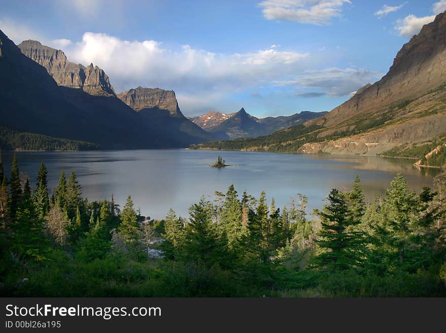 Small island in the center of a lake in Glacier National Park with surrounding mountains. Small island in the center of a lake in Glacier National Park with surrounding mountains