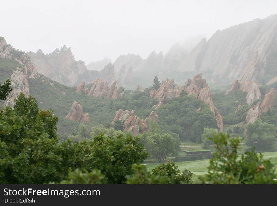 Jagged red rock outcroppings of Roxborough State Parkdisappearing into the fog with abundant green scrub oak. Jagged red rock outcroppings of Roxborough State Parkdisappearing into the fog with abundant green scrub oak