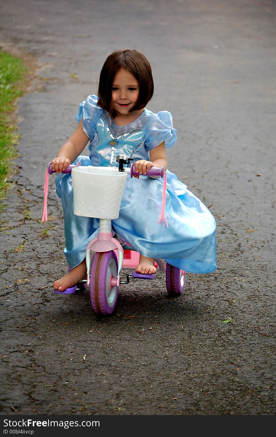 Four year old girl dressed up in a princess gown while riding a pink tricycle. Four year old girl dressed up in a princess gown while riding a pink tricycle.