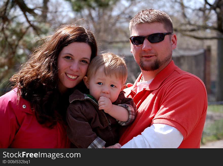 Young woman and young man holding a one year old boy who is sucking his thumb. Young woman and young man holding a one year old boy who is sucking his thumb.